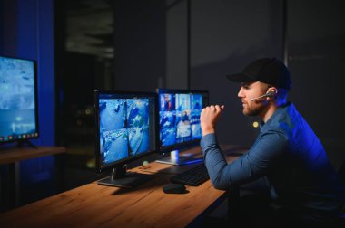 Erkek güvenlik görevlisi modern CCTV kameralarını içeride izliyor..