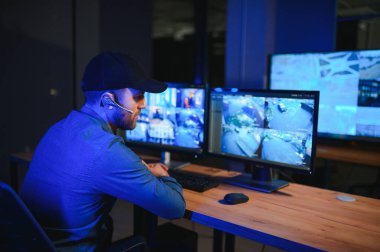 Erkek güvenlik görevlisi modern CCTV kameralarını içeride izliyor..