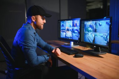 Güvenlik sistemi operatörünün ofis masasındaki kamera görüntülerine bakması..