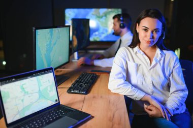 Ofiste bilgisayar kullanan, kulaklıklı, güler yüzlü bir kadın çağrı merkezi operatörü..