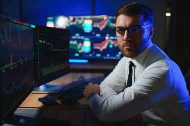 Gecenin geç saatlerinde borsa verilerini karşılaştıran iş adamı .