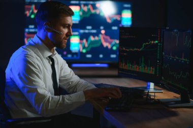 Ofis masasında oturan kripto simsarının yan görünüşü, pazarı analiz etmek, ekrana bakmak..