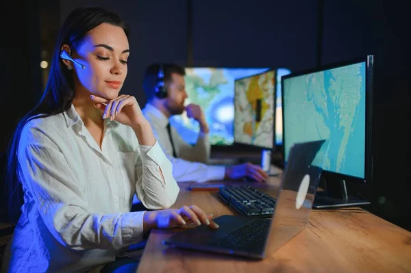 Ofiste bilgisayar kullanan, kulaklıklı, güler yüzlü bir kadın çağrı merkezi operatörü..