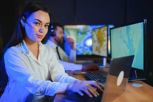 Ofiste bilgisayar kullanan, kulaklıklı, güler yüzlü bir kadın çağrı merkezi operatörü..