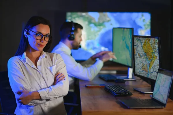 Ofiste bilgisayar kullanan, kulaklıklı, güler yüzlü bir kadın çağrı merkezi operatörü..