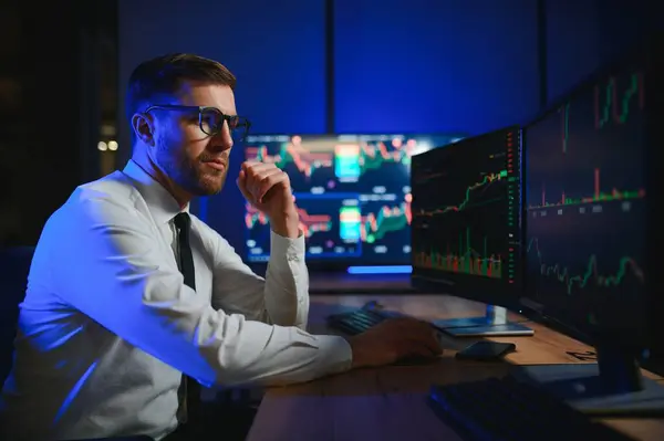 夜遅くに株式市場のデータを比較するビジネスマン ストック画像