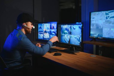 Güvenlik operatörü gece ofisindeki güvenlik kameralarını kontrol ediyor. Modern güvenlik sistemi ve sosyal güvenlik kavramı.