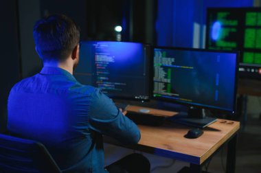 Gece Ofisi: Masaüstü Bilgisayarında Çalışan Genç Yakışıklı Adam. Dijital Girişimci Daktilo Kodu, Modern Yazılım Geliştirme, E-Ticari Uygulama Tasarımı, E-İş Geliştirme. Omuz üstünden.