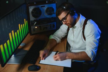 Erkek bir casus, konuşmaları makara teybe kaydeder ve dinler..