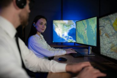 Tamirat merkezi. Seyrüsefer kontrol panosunda otururken kulaklıkla çalışan neşeli kadın ve erkek portresi.