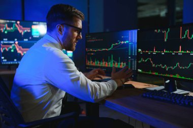 Gecenin geç saatlerinde borsa verilerini karşılaştıran iş adamı .