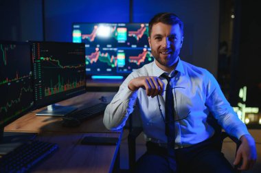 Ofis masasında oturan kripto simsarının yan görünüşü, pazarı analiz etmek, ekrana bakmak..