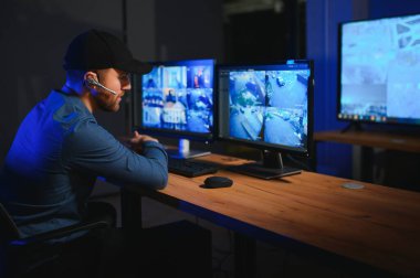 Güvenlik sistemi operatörünün ofis masasındaki kamera görüntülerine bakması..