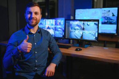 Erkek güvenlik görevlisi modern CCTV kameralarını içeride izliyor..