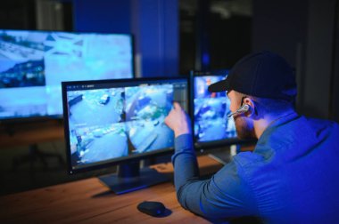 Güvenlik sistemi operatörünün ofis masasındaki kamera görüntülerine bakması..