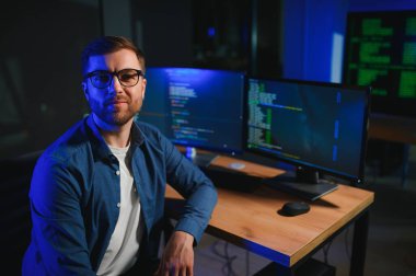 Gece Ofisi: Masaüstü Bilgisayarında Çalışan Genç Yakışıklı Adam. Dijital Girişimci Daktilo Kodu, Modern Yazılım Geliştirme, E-Ticari Uygulama Tasarımı, E-İş Geliştirme. Omuz üstünden.