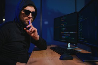 Bilgisayar ve dizüstü bilgisayar kullanarak virüs fidye virüsü kodlayan aranan hackerlar. Siber saldırı, sistem kırma ve kötü amaçlı yazılım kavramı.