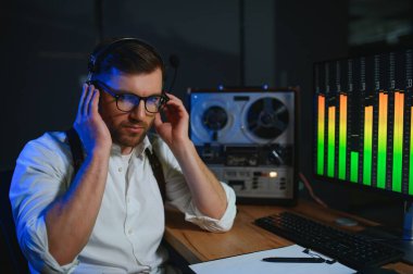 Erkek bir casus, konuşmaları makara teybe kaydeder ve dinler..