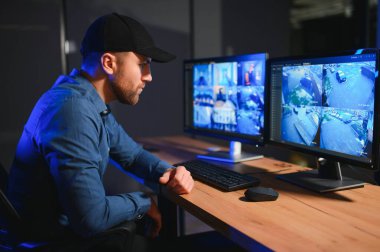 Güvenlik operatörü gece ofisindeki güvenlik kameralarını kontrol ediyor. Modern güvenlik sistemi ve sosyal güvenlik kavramı.