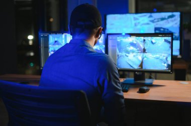 Güvenlik sistemi operatörünün ofis masasındaki kamera görüntülerine bakması..