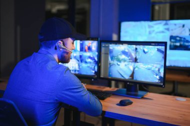 Güvenlik sistemi operatörünün ofis masasındaki kamera görüntülerine bakması..