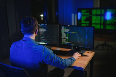 Gece Ofisi: Masaüstü Bilgisayarında Çalışan Genç Yakışıklı Adam. Dijital Girişimci Daktilo Kodu, Modern Yazılım Geliştirme, E-Ticari Uygulama Tasarımı, E-İş Geliştirme. Omuz üstünden.