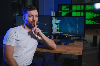 Beyaz masadaki masaüstü bilgisayarında çalışan erkek programcı.