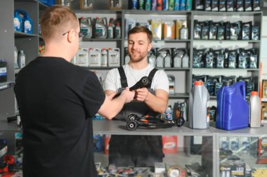 Bir müşteri oto yedek parça dükkanında danışmanla konuşur..