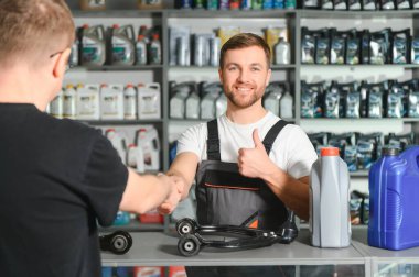 Bir müşteri oto yedek parça dükkanında danışmanla konuşur..