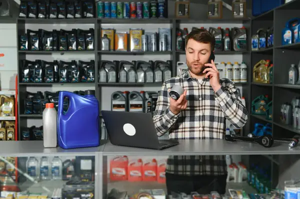 A salesman in an auto parts store is talking to a customer on the phone.