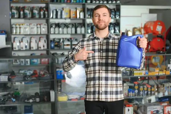 seller man with canister of motor oil in auto store.