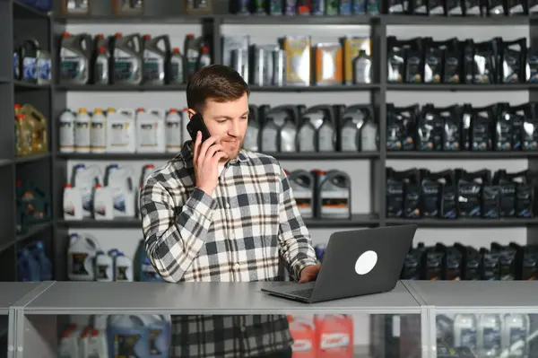 A salesman in an auto parts store is talking to a customer on the phone.