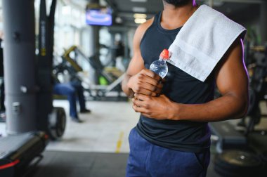 Afrikalı Amerikalı vücut geliştirici modern spor salonunda su bardağı tutuyor..