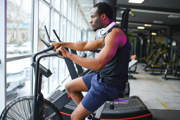 Attractive man at health club, exercising on bike.