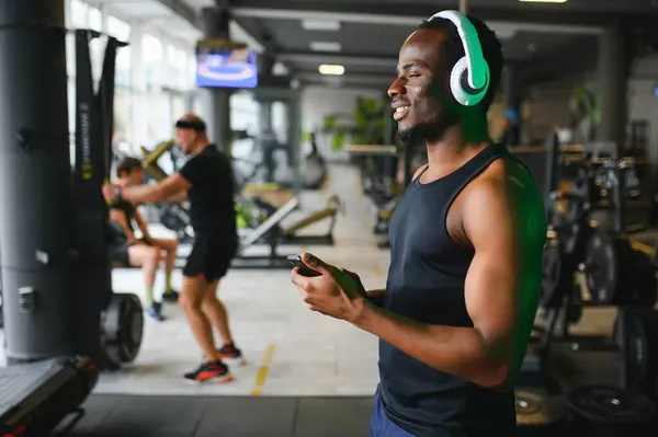African American man listening motivational music over headphones improving quality of workout.