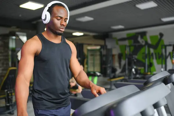 African American man listening motivational music over headphones improving quality of workout.
