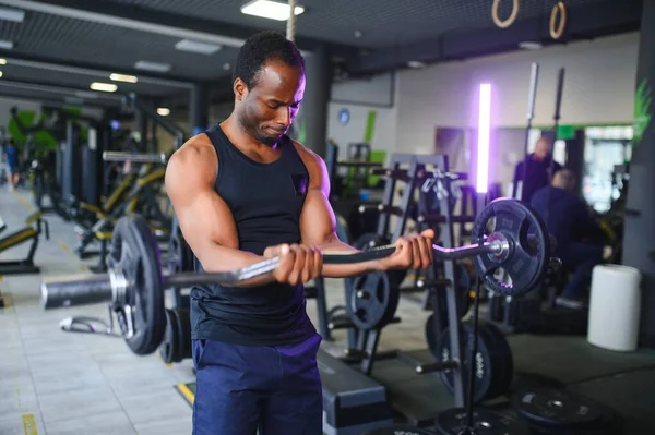 Athletic black guy making weightlifting or powerlifting at modern gym.