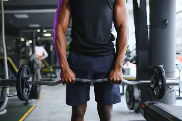 Athletic black guy making weightlifting or powerlifting at modern gym.