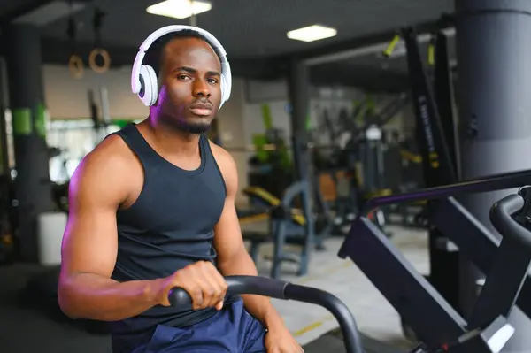 Athletic black man doing cardio workout on exercise bike in gym. Concept of sport and healthy lifestyle.