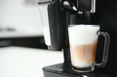 Modern kahve makinesi, mutfakta beyaz mermer tezgahın üzerinde cam bir fincan latte..