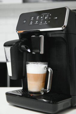 Modern kahve makinesi, mutfakta beyaz mermer tezgahın üzerinde cam bir fincan latte..