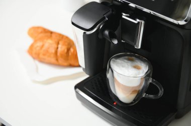 Modern kahve makinesi, mutfakta beyaz mermer tezgahın üzerinde cam bir fincan latte..