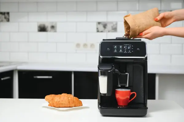 blurred background of kitchen and coffee machine with red cup and space for you.