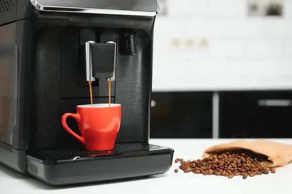 blurred background of kitchen and coffee machine with red cup and space for you.