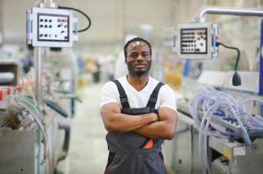 Üniformalı ve endüstriyel fabrikada ayakta duran Afrikalı Amerikalı erkek mühendisin portresi.