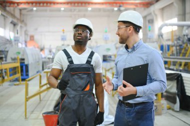 Bir mühendis üretim hattındaki bir işçiyle iletişim kurar..