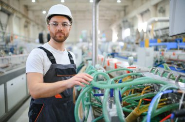 Özel üniformalı ve beyaz kasklı bir erkek işçi. PVC pencereleri için çerçeve üretimi.