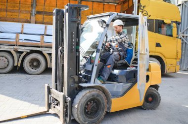 Fabrika deposundaki profesyonel forklift sürücüsünün portresi..