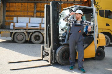 Fabrika deposundaki profesyonel forklift sürücüsünün portresi..