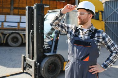 Ağır endüstri forklift sürücüsünün portresi baş parmak kaldırıyor ve gülümsüyor..